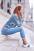 Woman with closed eyes sitting and relaxing on stairs