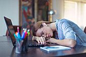Young tired businesswoman sleeping on desk in home office