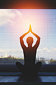 Silhouette of woman doing yoga pose at home at sunset