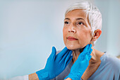 Doctor examining a senior woman's neck
