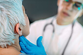 Doctor examining a senior woman's neck