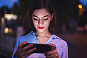 Young businesswoman reading news on smartphone at night