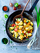 Scrambled tofu in a pan with tomatoes and chilies