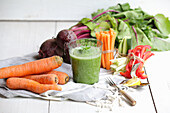 Freshly squeezed vegetable juice surrounded by fresh vegetables