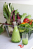 Freshly squeezed vegetable juice behind basket of vegetables