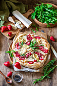 Strawberry pizza with chicken fillet, brie cheese, poppy seeds, rosemary and rocket salad