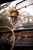 Happy young woman outside convertible in park