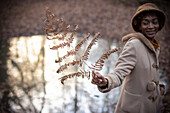 Young woman holding autumn branch in park