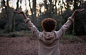 Carefree young woman with arms raised in park