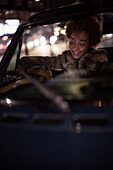 Young woman using smartphone in convertible at night