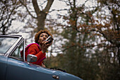 Young woman with digital camera in convertible in park