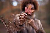 Young woman holding autumn leaf