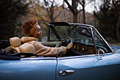 Young woman driving convertible in park