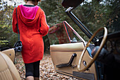 Young woman getting out of convertible in park