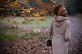Happy young woman in coat in park
