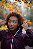 Young female runner in rain jacket in park