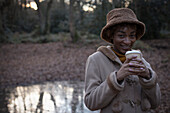 Happy young woman drinking coffee in park
