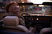 Happy young woman driving convertible at night