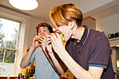 Hungry teenage boys eating hamburgers in kitchen