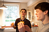 Happy teenage boys eating pizza in kitchen