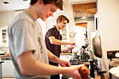 Teenage boys cooking at home in kitchen