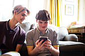Teenage boys using smartphone in living room