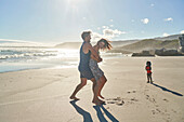 Happy playful couple hugging on sunny summer ocean beach