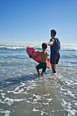 Father and son with body board in sunny summer ocean
