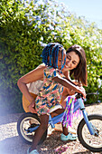 Mother helping cute toddler daughter ride bike