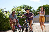 Happy family riding bikes in sunny driveway