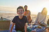 Boy with sandy face on sunny beach with family