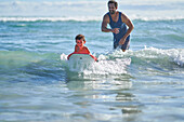 Happy father and son body boarding in sunny ocean