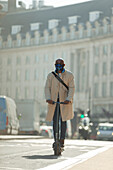 Businessman in face mask riding electric push scooter