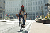 Male commuter riding bicycle on sunny city street