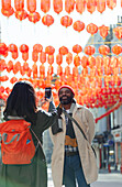 Woman photographing husband in Chinatown, London, UK