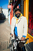 Confident man with bicycle on sunny sidewalk