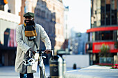 Happy businessman walking bicycle on city street