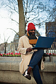 Businessman working at laptop in city park