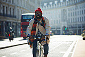 Happy businessman riding bicycle on city street, London, UK