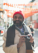 Male tourist with digital camera in sunny city