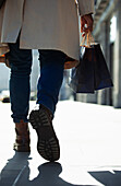 Man with shopping bags walking on sunny sidewalk