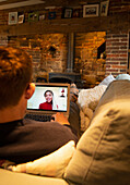 Man on sofa video conferencing with colleagues