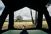 Woman relaxing inside tent in remote Australian bush