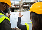 Architects with blueprints at construction site