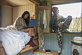 Couple relaxing and using laptop in tiny cabin rental