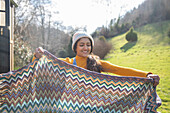 Young woman folding blanket at sunny campsite