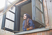 Carefree young woman looking out cabin window