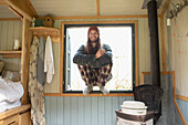 Happy young man in pyjamas in tiny cabin window