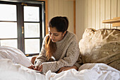 Young woman writing in bed