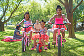 Carefree sisters riding bikes in sunny summer park